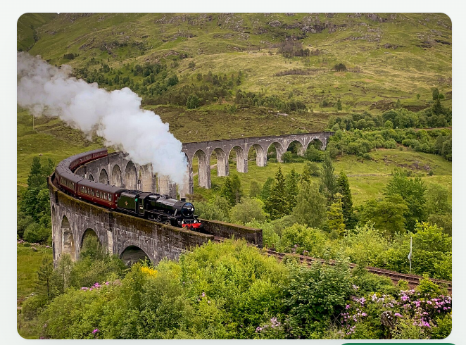 Steam train crossing a Scottish viaduct through green highland hills